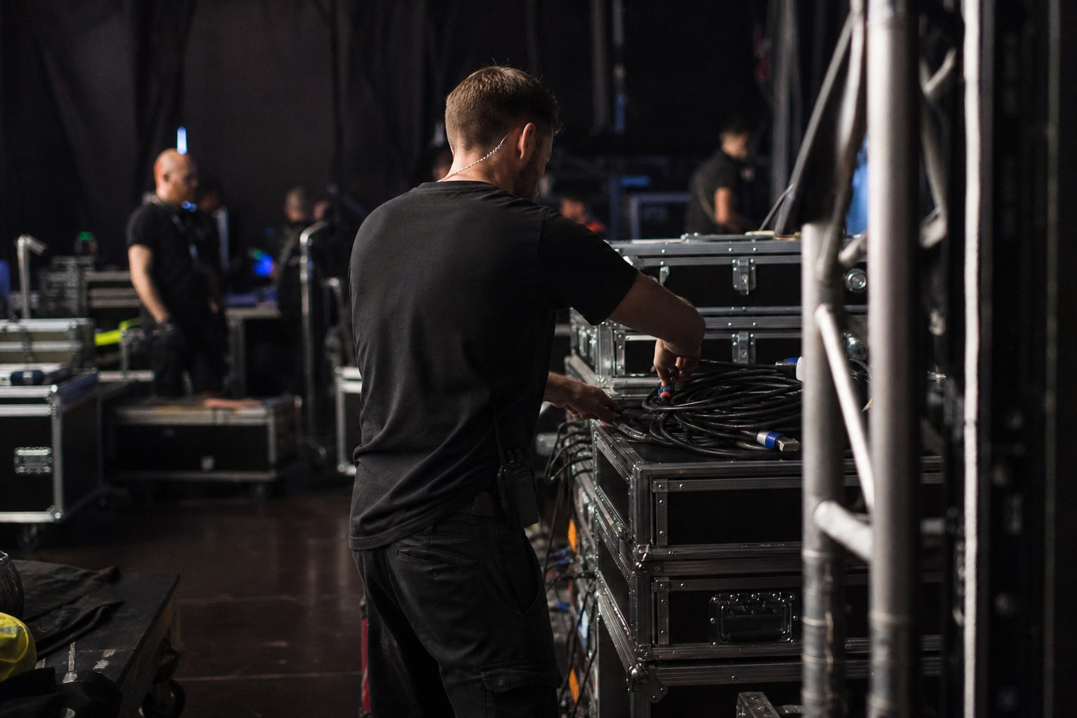 Agencja eventowa Grudziądz - backstage eventu z case'ami, kablami i ekipą w czerni podczas montażu